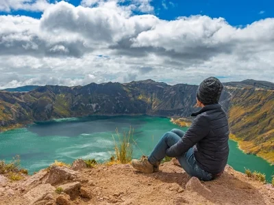 Kvinde sidder på kanten af kratersøen Quilotoa i Ecuador.