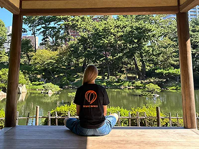 Kvinde i TourCompass-tshirt i smuk japansk have i Hiroshima