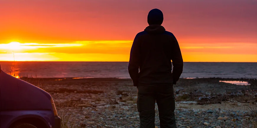 Mand nyder solnedgang ved vandet i New Zealand