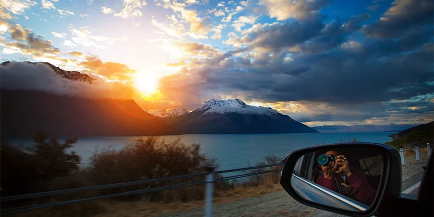 Mand tager billede ud af vinduet ved Lake Wakatipu på Sydøen i New Zealand